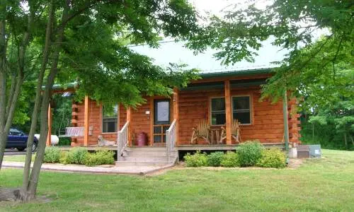 Una cabaña de madera detrás de árboles verdes