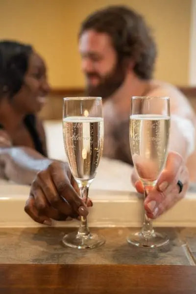 Pareja tomando champán en la bañera. 