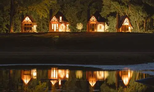 Cuatro cabinas iluminadas por la noche, reflejadas en el agua