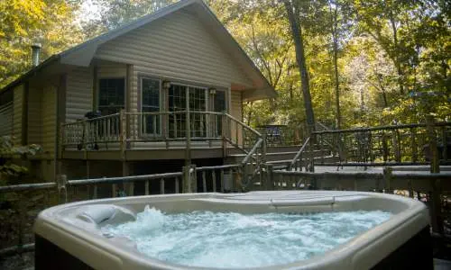 Un burbujeante jacuzzi frente a una cabaña entre los árboles