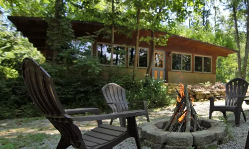 una casa con sillas y hoguera en el exterior