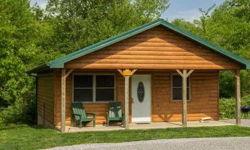 El exterior de una cabaña de madera rodeada de vegetación
