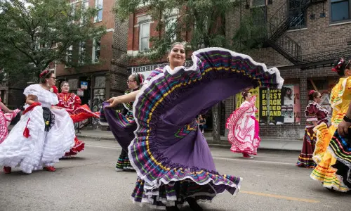 Bailarines folclóricos girando con sus trajes tradicionales durante un desfile callejero de « Chicago ».