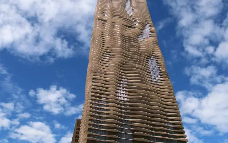El exterior de la Torre Aqua de Chicago, bajo un cielo azul lleno de nubes.