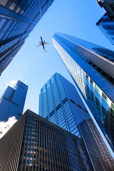 Mirando hacia el cielo, con los rascacielos de Chicago por todos lados y un avión de pasajeros pasando por encima.