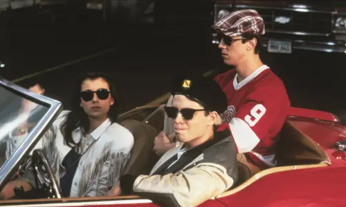 Imagen fija de la película Ferris Bueller's Day Off, con los tres protagonistas sentados en un Ferrari rojo descapotable.