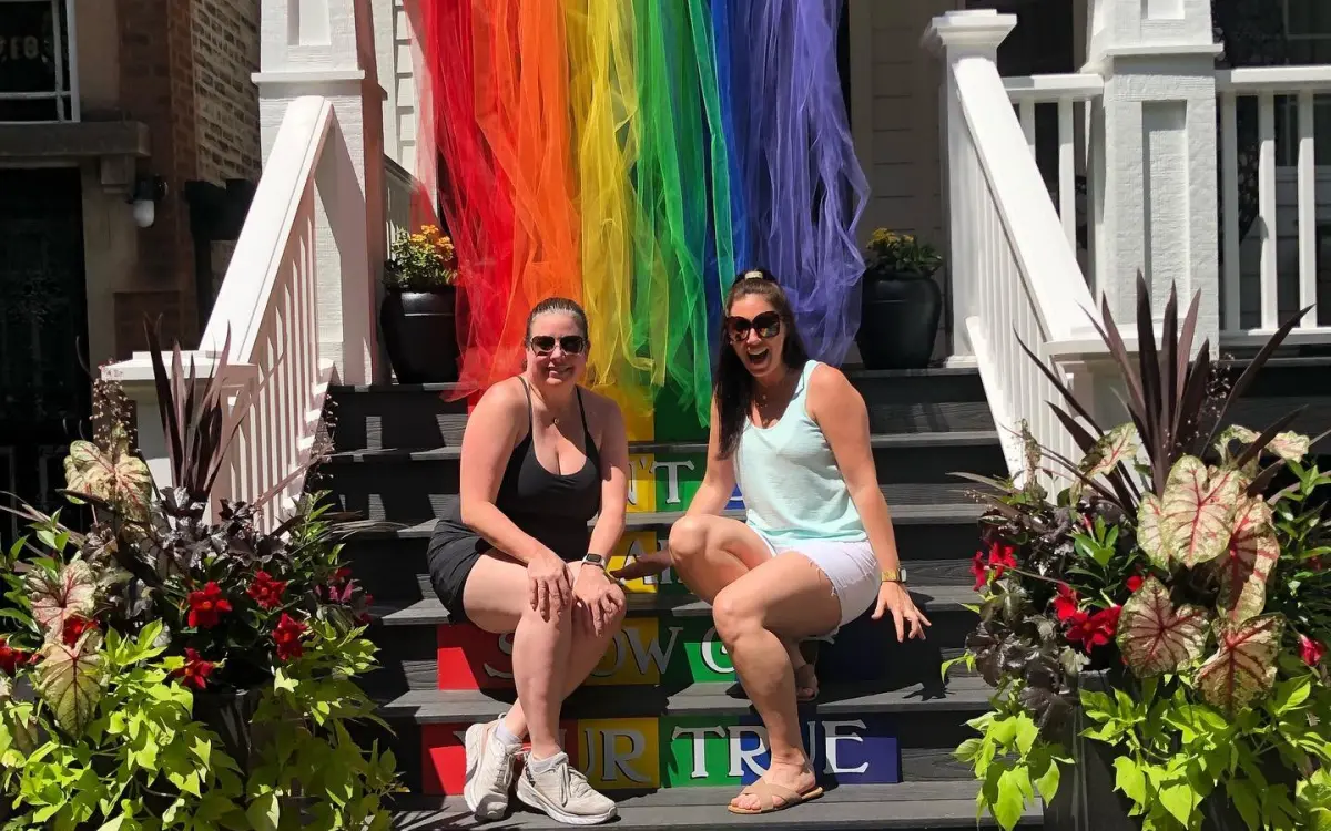 Chicas delante de la bandera del orgullo.