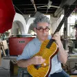Ian Schneller rasguea una guitarra fabricada por él.