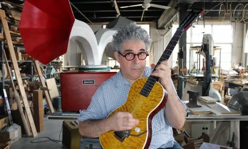 Ian Schneller rasguea una guitarra fabricada por él.