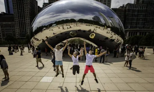 Tres personas saltan por los aires frente al monumento The Bean en Chicago