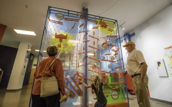Un niño juega con una exposición interactiva del museo, mientras los abuelos lo observan