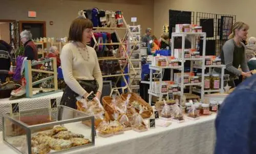 Una mujer detrás de una mesa con productos de panadería