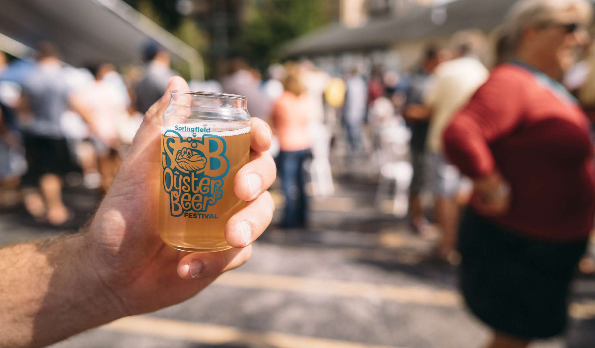 Alguien sostiene un tarro lleno de cerveza con la marca del Festival de la Cerveza y la Ostra de Springfield.