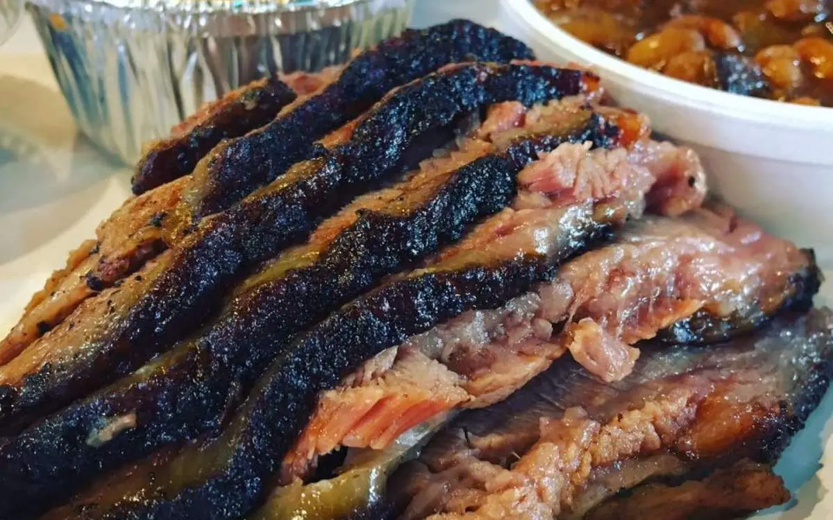 Una pila de carne a la barbacoa con frijoles y pan de maíz
