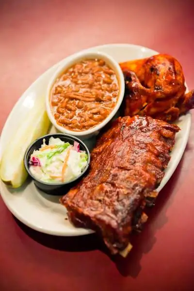 Un plato de barbacoa con costillas, ensalada y judías.