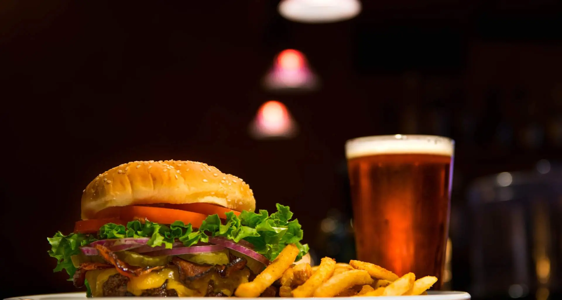 Una hamburguesa con patatas fritas y una cerveza