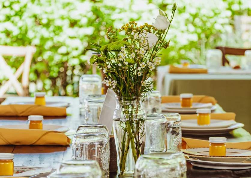 Una foto de platos alineados a lo largo de una mesa con flores en el centro