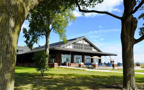 El exterior de un restaurante junto al lago con árboles en primer plano 
