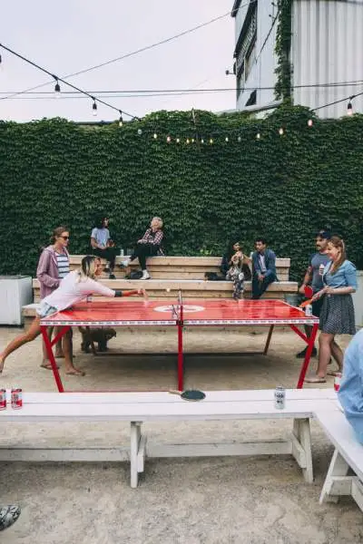 Clientes bebiendo cervezas y jugando al ping-pong al aire libre