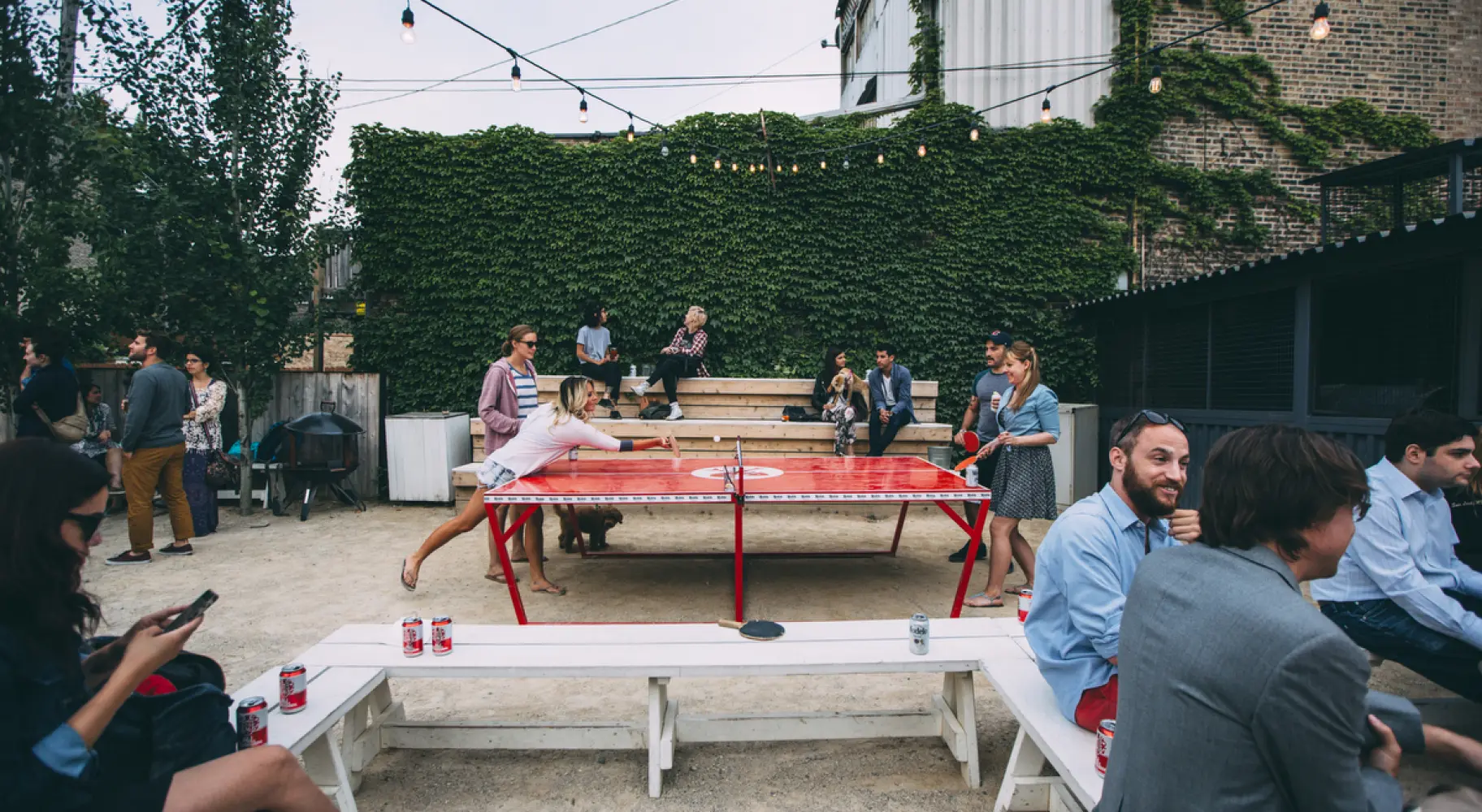Clientes bebiendo cervezas y jugando al ping-pong al aire libre