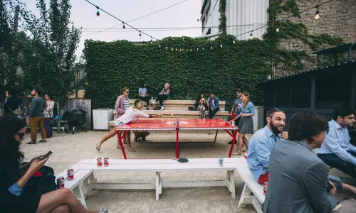 Clientes bebiendo cervezas y jugando al ping-pong al aire libre