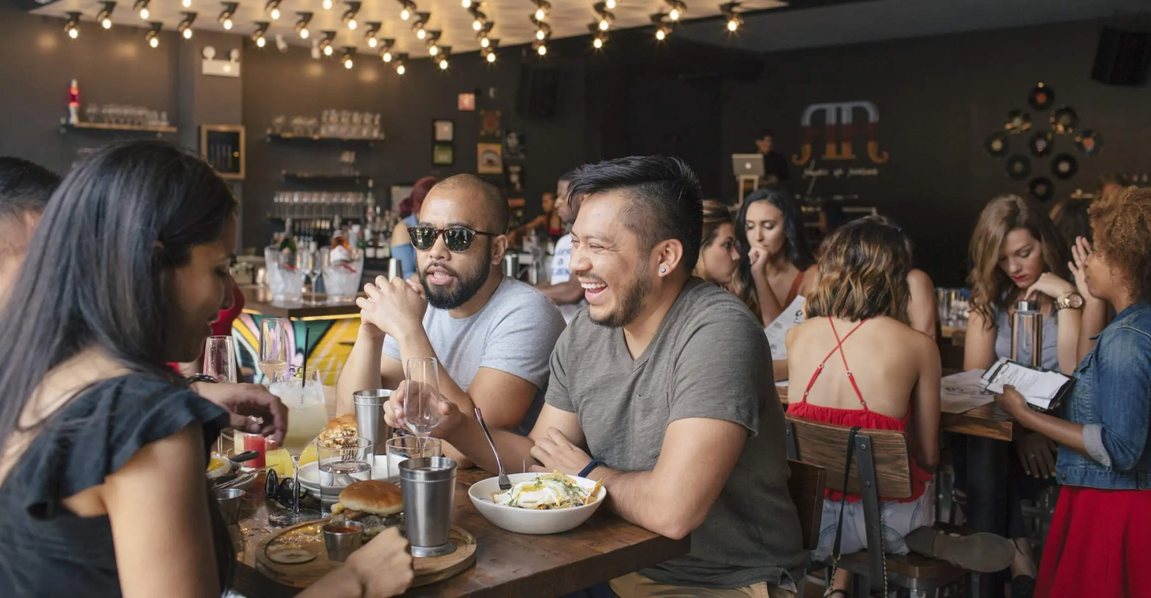 Tres amigos comiendo Brunch dentro de un concurrido bar y restaurante