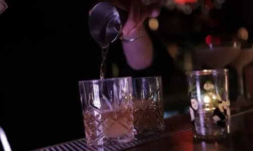 Un camarero sirve bebidas en vasos.