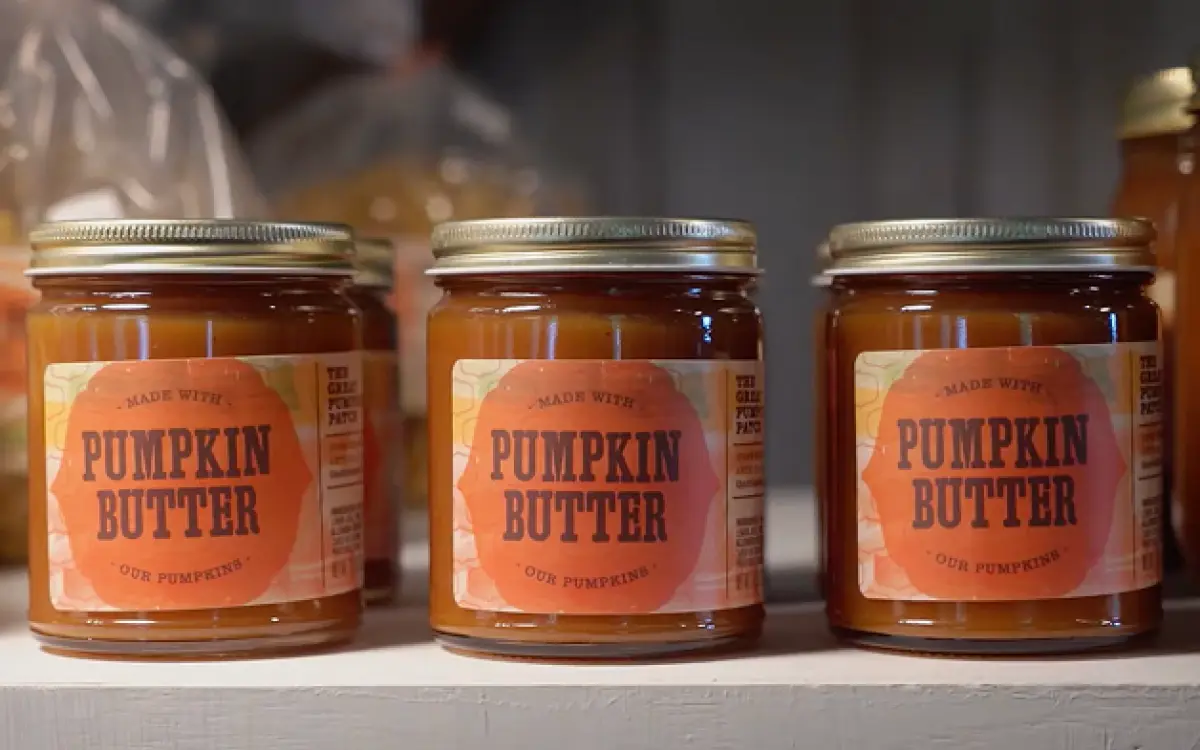 Tres tarros de cristal con la etiqueta «Mantequilla de calabaza» alineados en una estantería. 