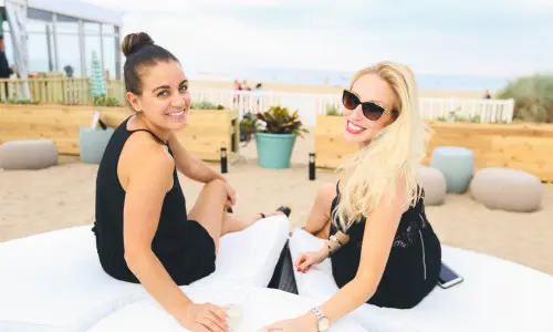 Dos mujeres tomando una copa en una tumbona de playa