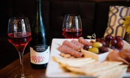 Un plato de queso y un par de copas de vino sobre una mesa