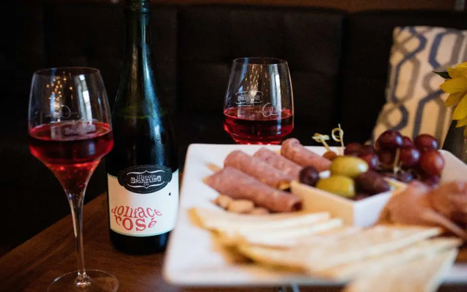 Un plato de queso y un par de copas de vino sobre una mesa