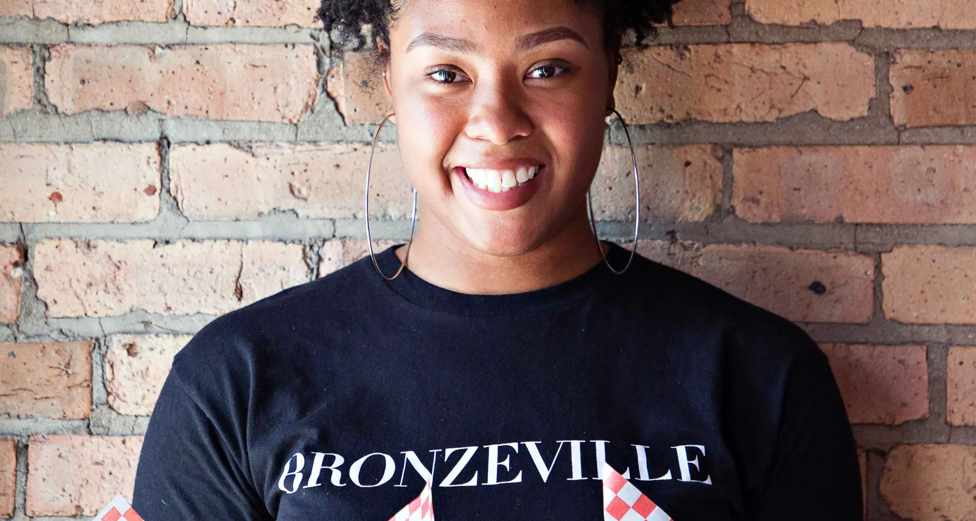 Mujer sosteniendo comida frente a un muro de ladrillos