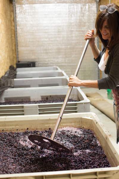 Una mujer mezcla las uvas en un gran recipiente para hacer vino.