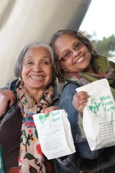Dos mujeres con bolsas de pollo frito de White Fence Farm