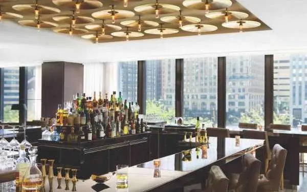 Interior de un bar con muchas ventanas que dan a la ciudad.