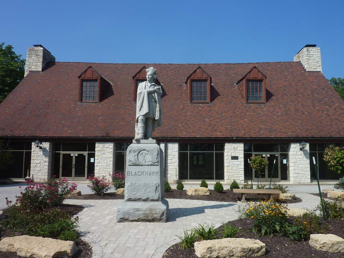 Una estatua de Blackhawk delante de un edificio bajo de dos plantas