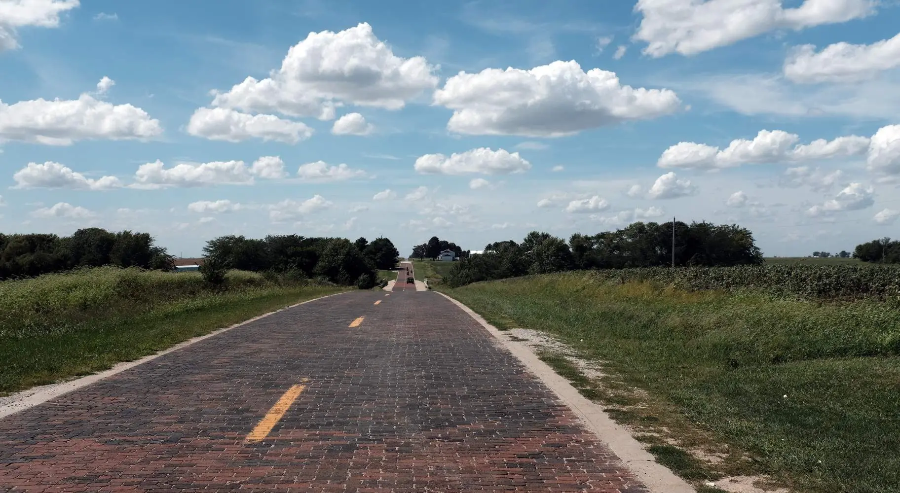 Una antigua carretera de ladrillos entre verdes campos rurales