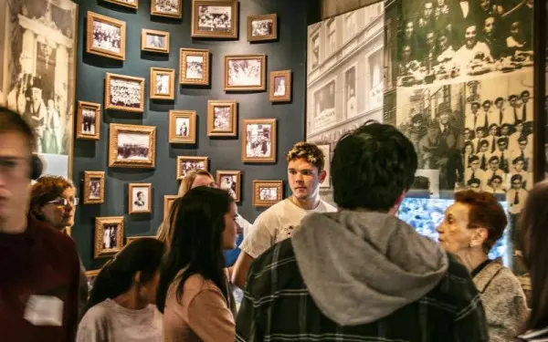 Visitantes del museo reunidos en una pequeña sala cubierta de fotografías
