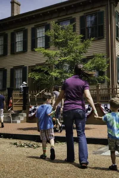 Una madre y sus hijos caminan hacia la casa de Lincoln en el Lincoln Home Historic Site de Springfield.