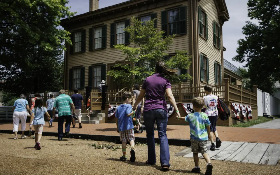 Una madre y sus hijos caminan hacia la casa de Lincoln en el Lincoln Home Historic Site de Springfield.
