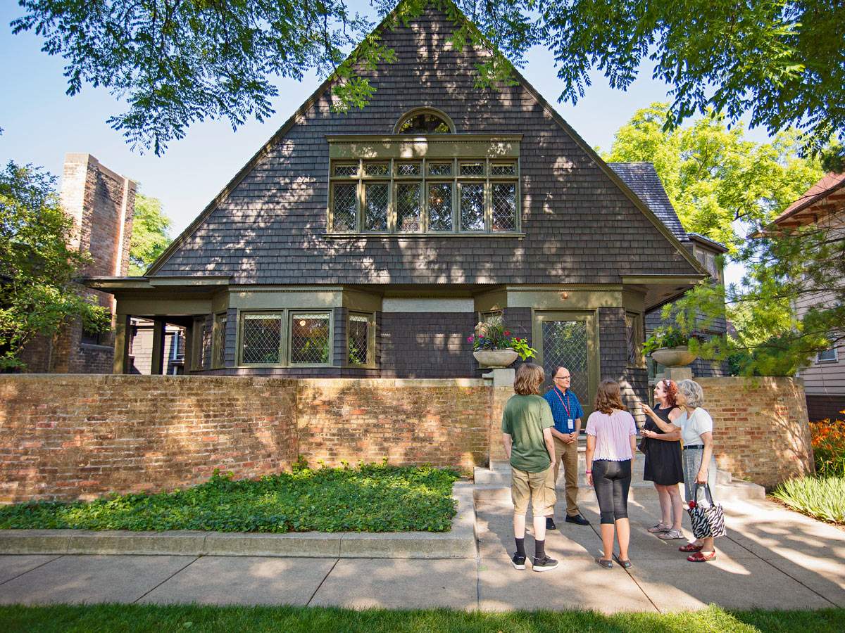 Un guía habla con un grupo de turistas en la acera frente a la casa y el estudio de Frank Lloyd Wright en Oak Park.