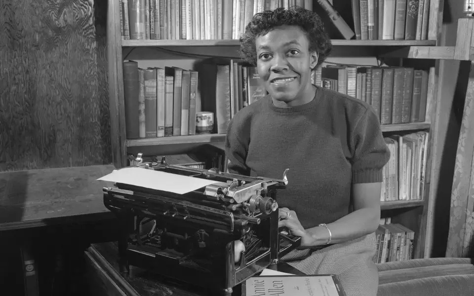 Mujer sentada frente a una máquina de escribir en una biblioteca