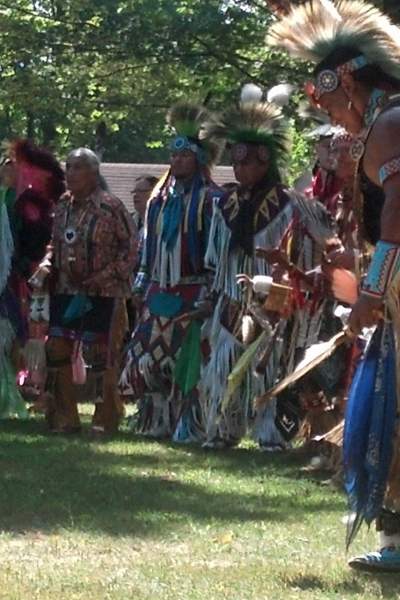 Un grupo de hombres con atuendo nativo americano en un claro de hierba entre árboles