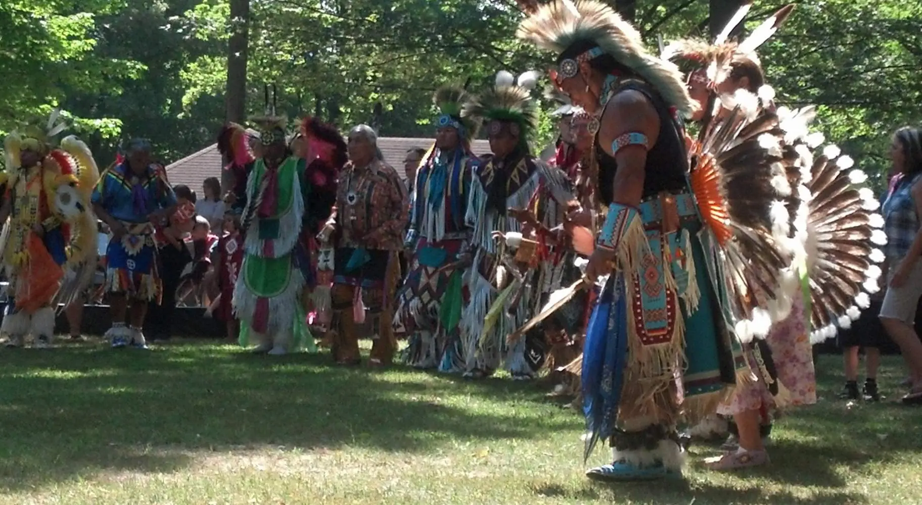 Un grupo de hombres con atuendo nativo americano en un claro de hierba entre árboles