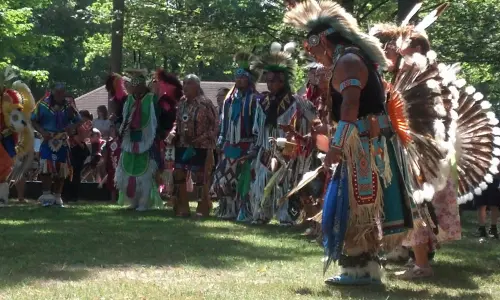Un grupo de hombres con atuendo nativo americano en un claro de hierba entre árboles