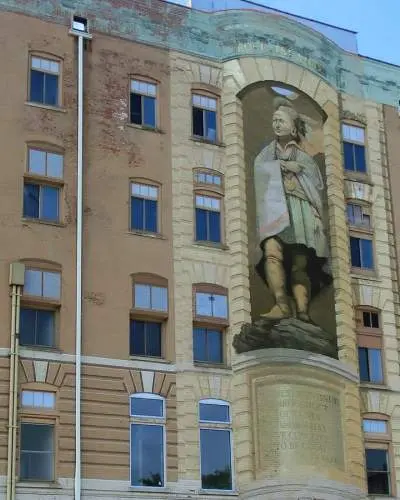 Un gran mural de Blackhawk de tres pisos de altura en la fachada de un edificio de ladrillo.