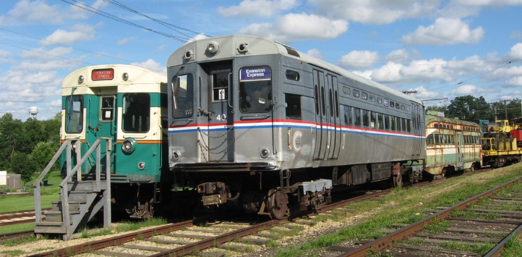 Un grupo de viejos trolebuses al aire libre sobre raíles en el Fox River Trolley Museum