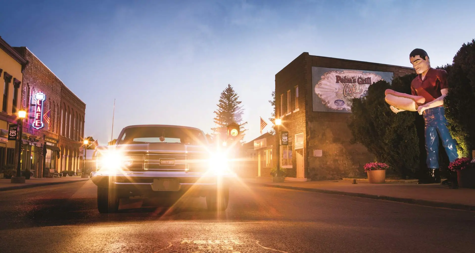 Un automóvil clásico con los faros encendidos, junto a la estatua gigante de Paul Bunyon en Atlanta