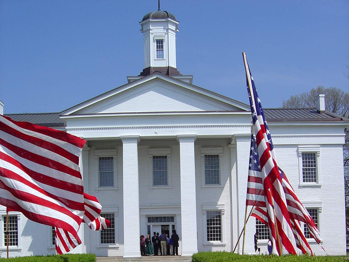 Una gran casa blanca con banderas americanas delante