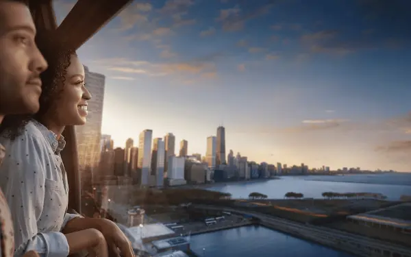 Pareja dentro de la Rueda Centenaria durante la puesta de sol con vistas a la ciudad.